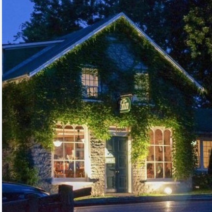 An ivy-covered stone cottage lit up at night